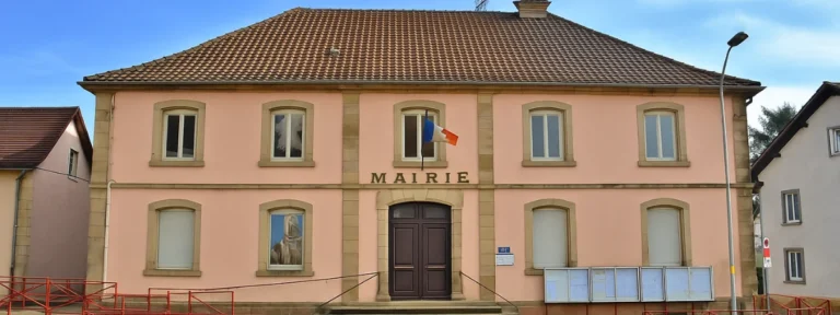 Mairie de Danjoutin avec façade rose et drapeau français, bâtiment typique du Territoire de Belfort – Danjoutin – Élagage Belfort