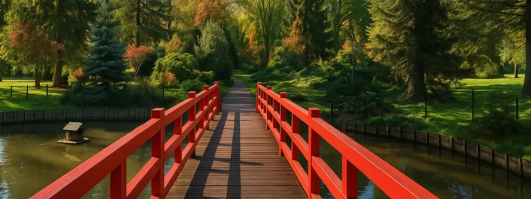Passerelle en bois rouge traversant l’étang du parc du Près-la-Rose à Montbéliard, entourée d’arbres colorés – Montbéliard – Élagage Belfort